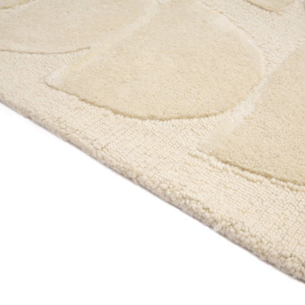 Close-up of a textured beige rug corner with curved patterns on a white background