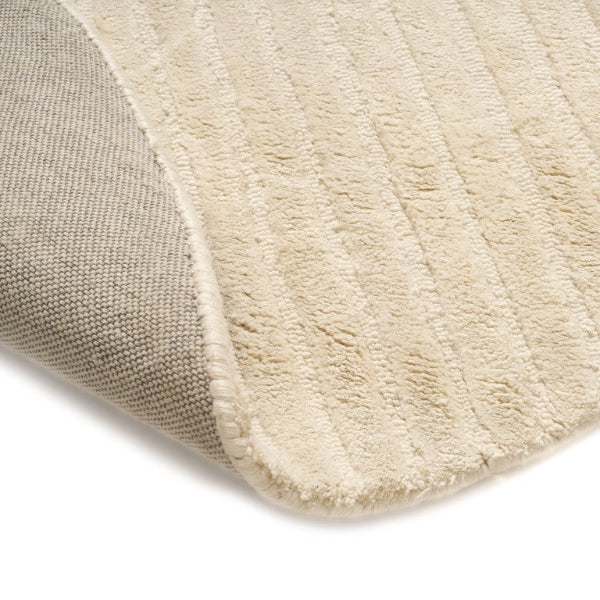 Close-up of a textured beige rug corner on a white background