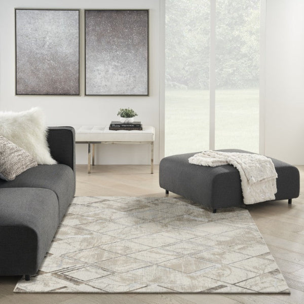 Modern living room with gray sofa, ottoman, and abstract art on the wall.