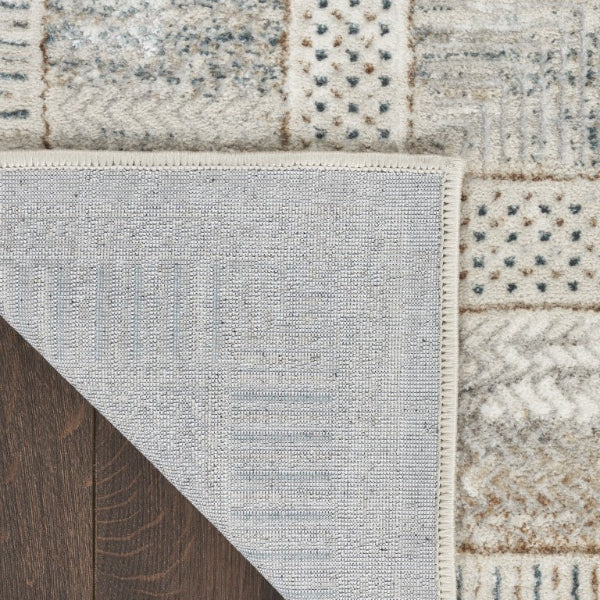 Close-up of a textured rug corner transitioning from gray to multicolor pattern.