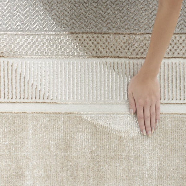 Hand touching a textured beige rug with intricate patterns