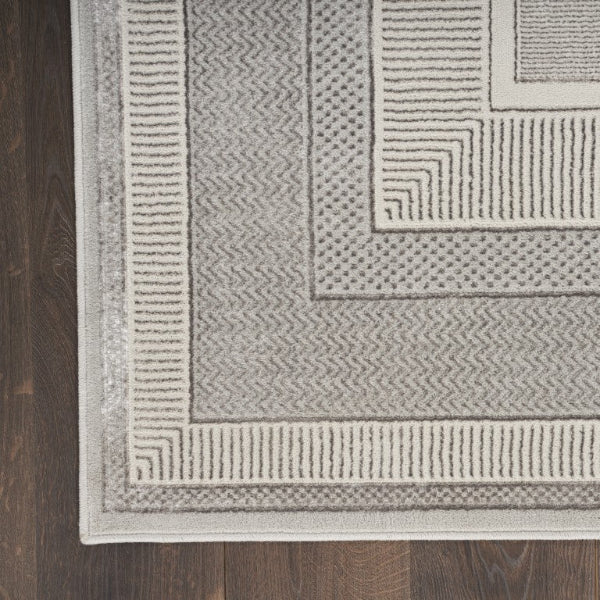 Close-up of a textured gray rug with geometric patterns on a wooden floor.