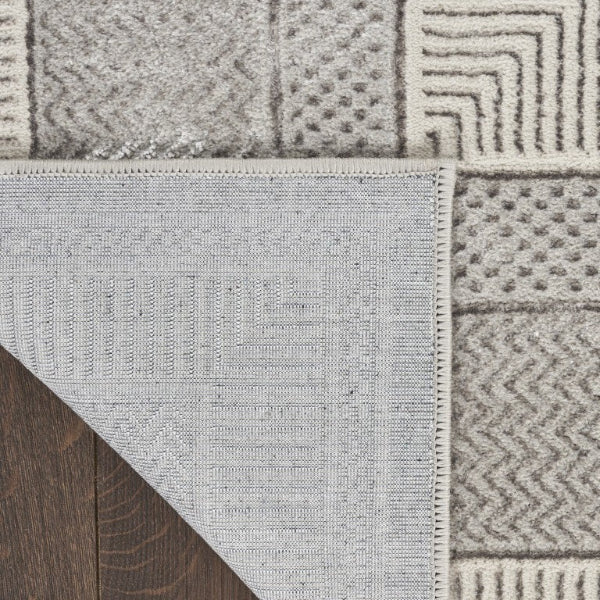 Close-up of a textured rug with geometric patterns on a wooden floor.