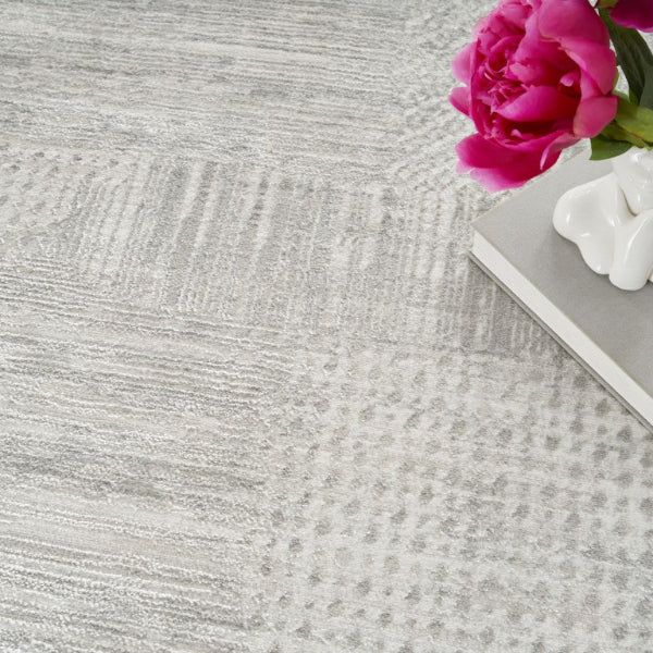 Close-up of a textured gray surface with a pink flower and white object on a gray surface.