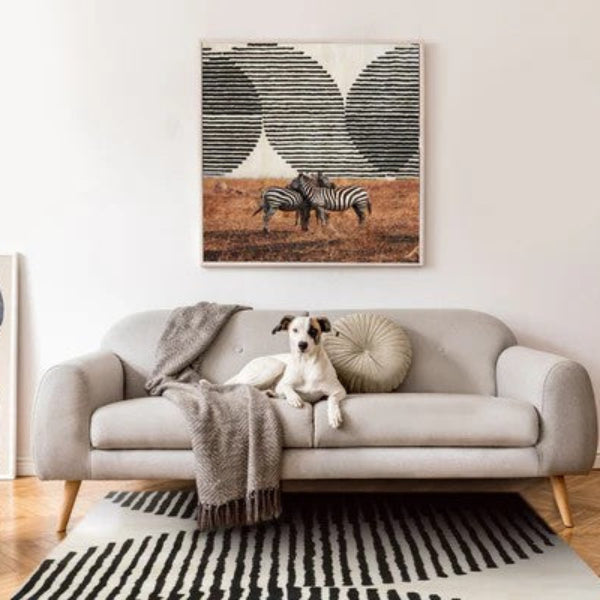 Living room with a gray sofa, decorative pillows, and a painting of zebras on the wall.