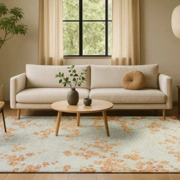 Louis De Poortere Sakura rug with floral design in beige and orange under a modern beige sofa in a stylish living room