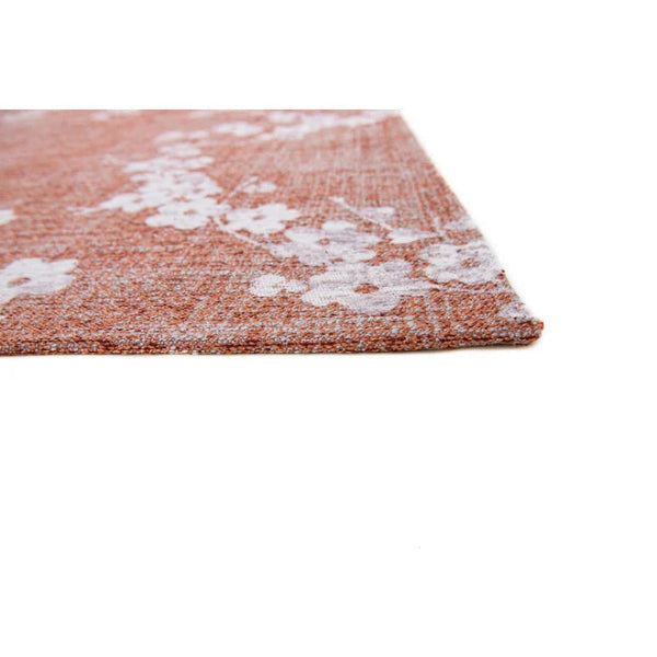 Close-up of Louis De Poortere Sakura rug showcasing floral design on rust background