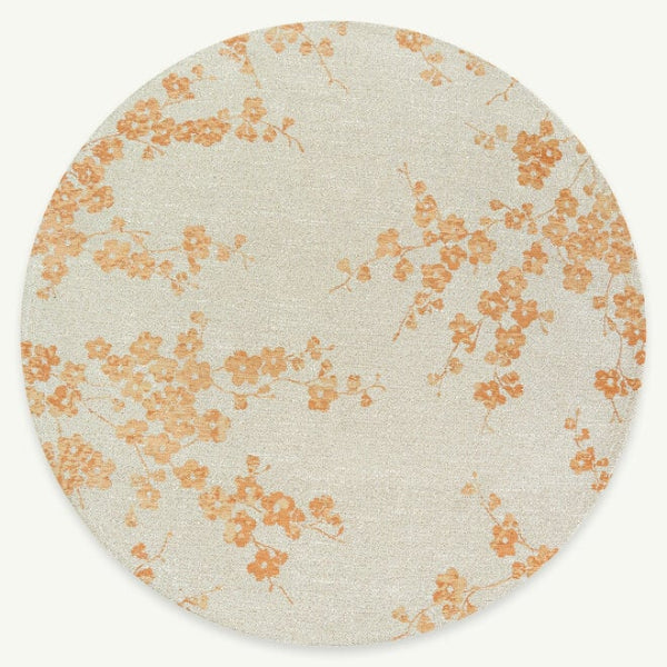 Round luxury Louis De Poortere Sakura rug with delicate orange floral pattern on a light background