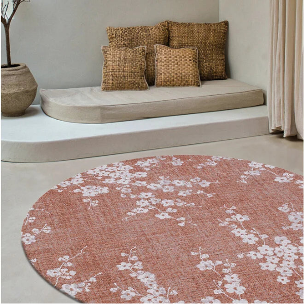 Round Louis De Poortere Sakura rug with pink background and white floral cherry blossom pattern in modern living room