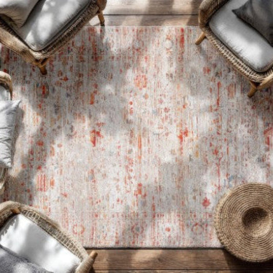 Luxury Louis De Poortere Ushak rug with soft neutral tones and subtle red accents under wicker chairs