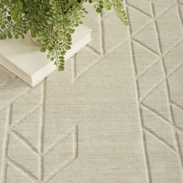 Close-up of beige Nourison Alessia rug showcasing geometric pattern beneath a green potted plant