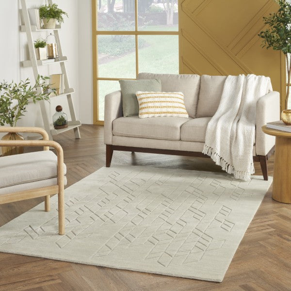 Luxury living room with Nourison Alessia rug featuring embossed geometric patterns under beige sofa and wooden furniture