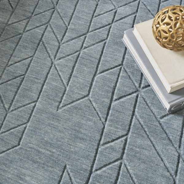 Luxury Nourison Alessia rug in blue with geometric pattern texture under decorative books and sculpture