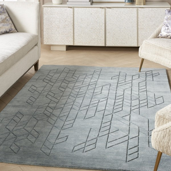 Nourison Alessia rug in grey with geometric pattern placed in a modern living room between sofas