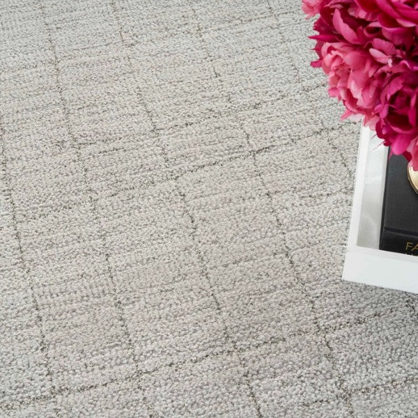 Close-up of a textured beige luxury rug with subtle grid pattern from Nourison Andes Rug Collection next to pink flowers
