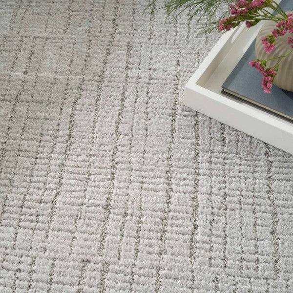Close-up of textured grey luxury rug from Nourison Andes Rug Collection with decorative tray and flowers