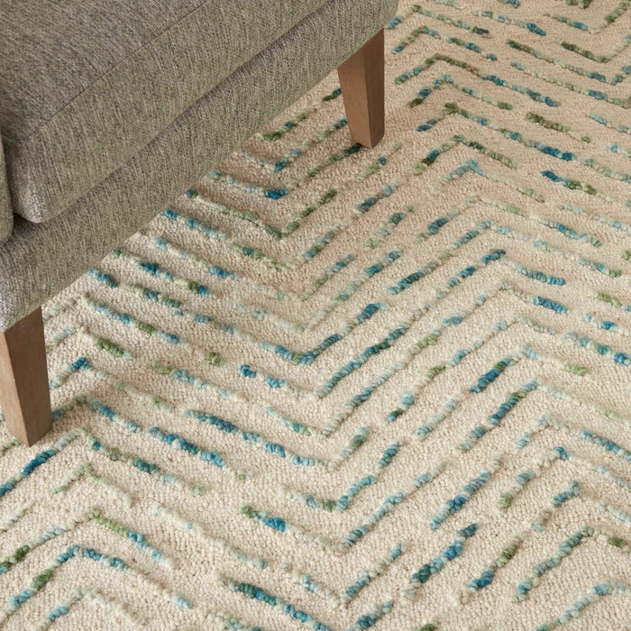 Close-up of Nourison Colorado Rug Geometric Design in beige with blue and green accents under wooden sofa legs
