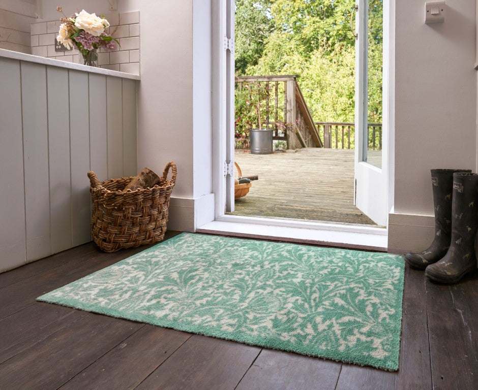 Turtle Mats Thistle Design indoor Mat in green and white placed on wooden floor by an open door