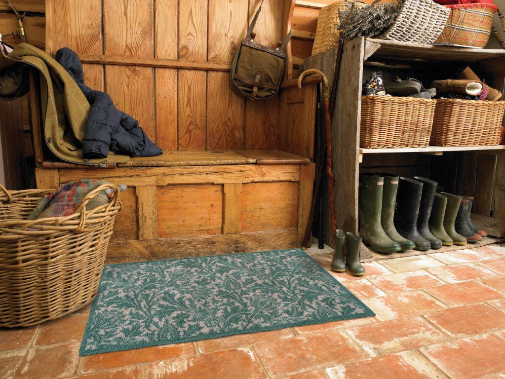 Turtle Mats Thistle Design indoor Mat placed on rustic tiled floor in wooden mudroom with boots and storage baskets