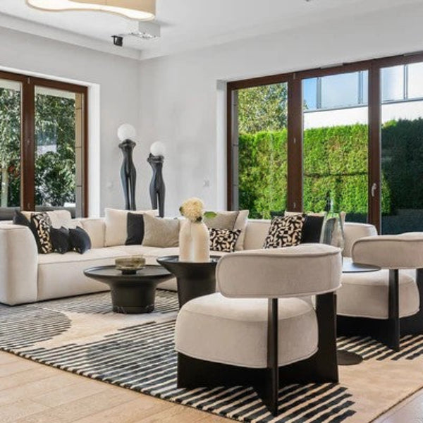 Modern living room with white sofa, ottomans, and large windows.