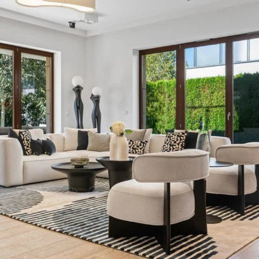 Modern living room with white sofa, ottomans, and large windows.
