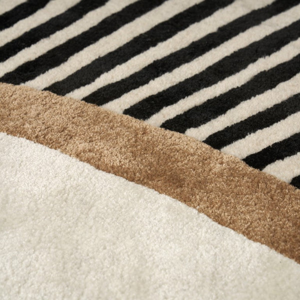 Close-up of a rug with black and white striped pattern and brown border.