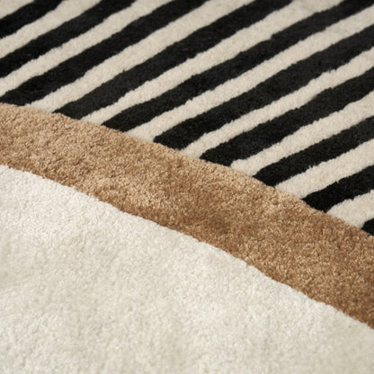 Close-up of a rug with black and white striped pattern and brown border.