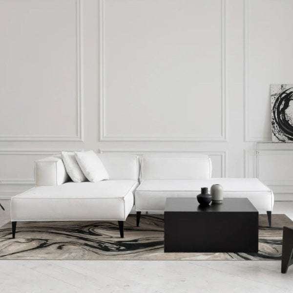 Modern living room with white sofa, black coffee table, and abstract art on wall.