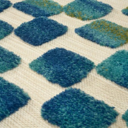 Close-up of a textured rug with blue and green diamond pattern