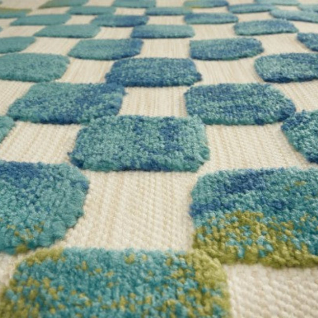 Close-up of a textured rug with blue and green pattern on a beige background