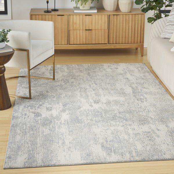 Gray area rug in a living room with wooden furniture and decor.