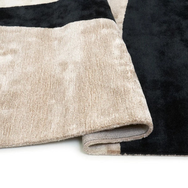 Close-up of a folded beige and black rug on a white surface