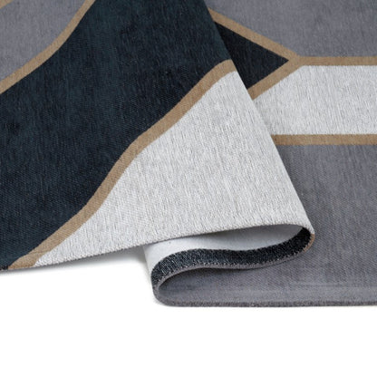 Close-up of a geometric-patterned rug with a white base and black, gray, and brown accents.