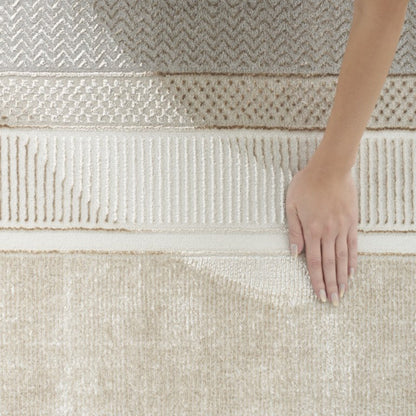 Hand touching a textured beige rug with intricate patterns