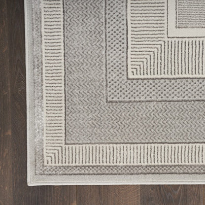 Close-up of a textured gray rug with geometric patterns on a wooden floor.