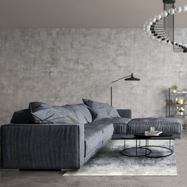 Modern living room with a gray sectional sofa and concrete wall.