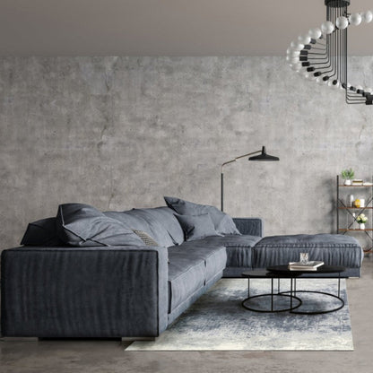 Modern living room with a gray sectional sofa and concrete wall.