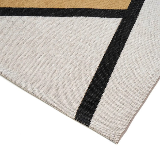 Close-up of a geometric-patterned rug with black, beige, and white colours.