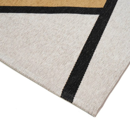 Close-up of a geometric-patterned rug with black, beige, and white colours.