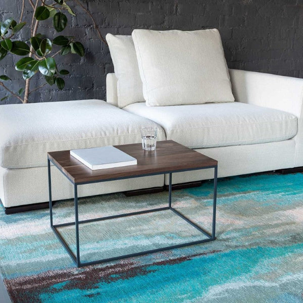 White sectional sofa with a coffee table on a colorful rug in a modern living room.