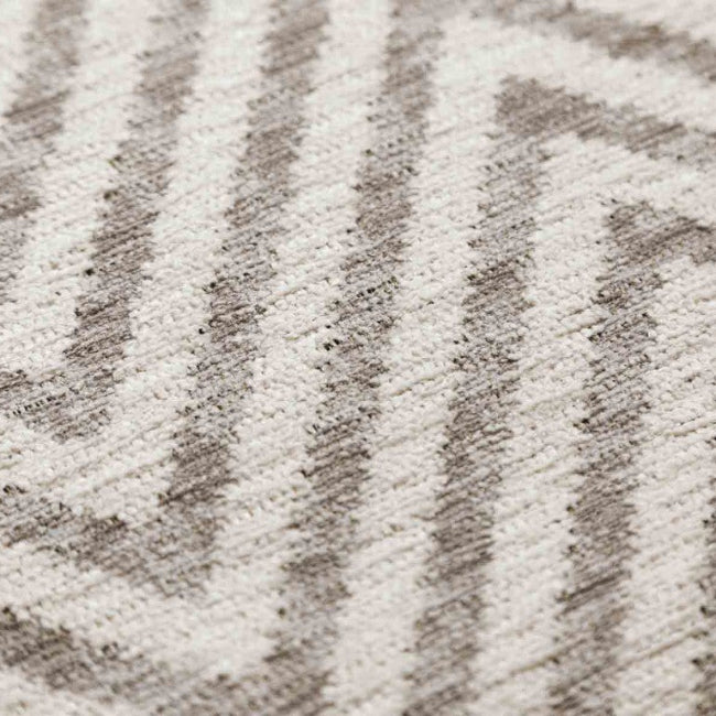 Close-up of a textured rug with a chevron pattern in neutral colors.