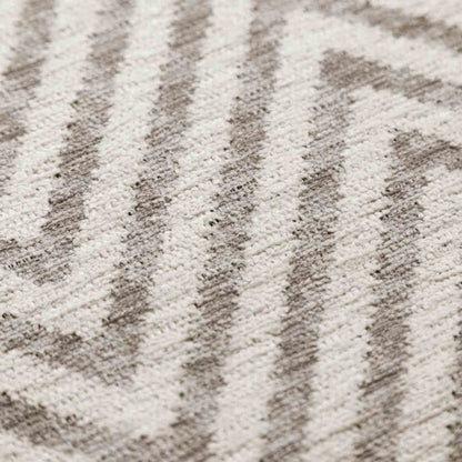 Close-up of a textured rug with a chevron pattern in neutral colors.