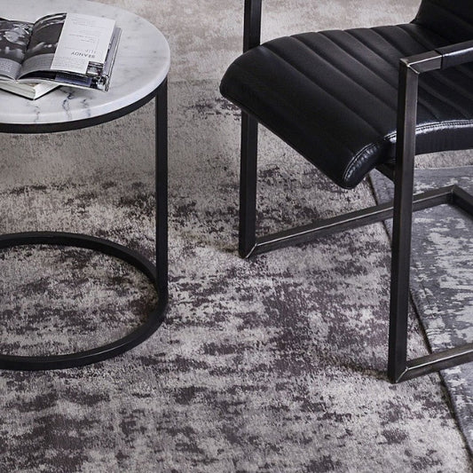 Black chair and round side table on a textured gray rug