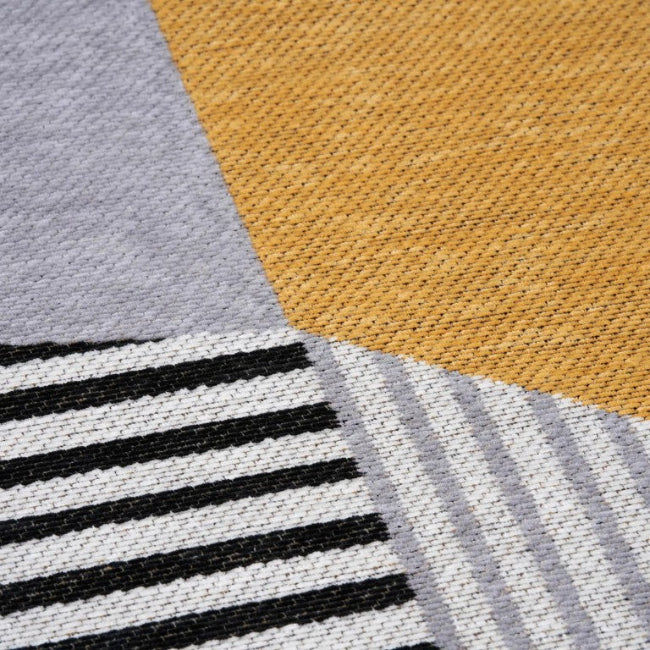Close-up of a textured fabric with black stripes, gray, and mustard yellow sections.