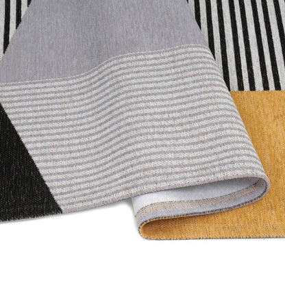 Close-up of textured fabric samples in gray, black, white, and yellow on a striped background.