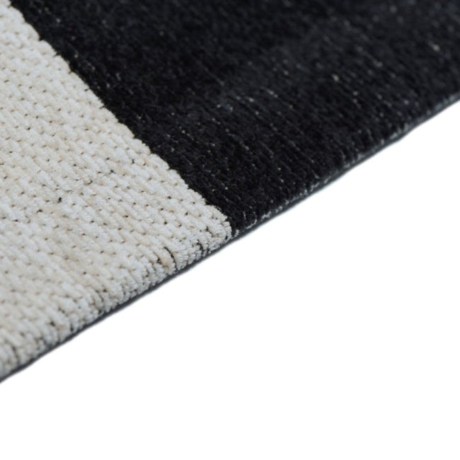 Close-up of a black and white textured rug corner on a white background