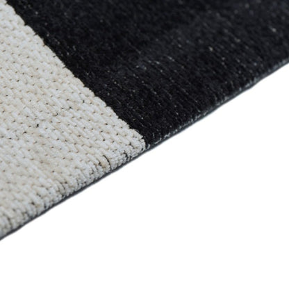 Close-up of a black and white textured rug corner on a white background