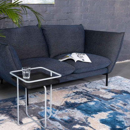 Gray sofa with a small table and plant in a modern living room setting.