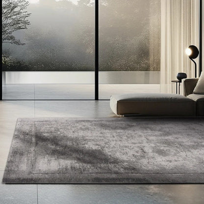 Modern living room with a gray rug, sofa, and large windows overlooking nature.