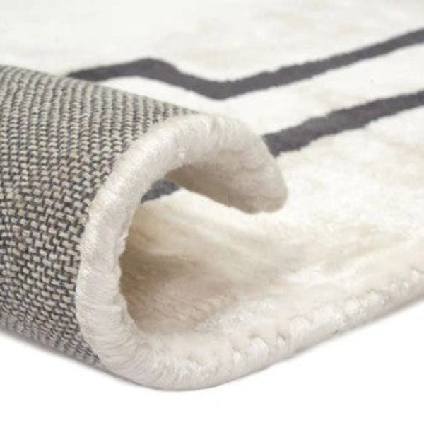 Close-up of a textured rug with a white and gray pattern on a white background